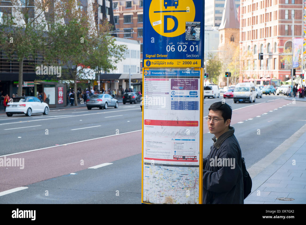 person asian male adult reading bus timetable wait for a bus at Stock