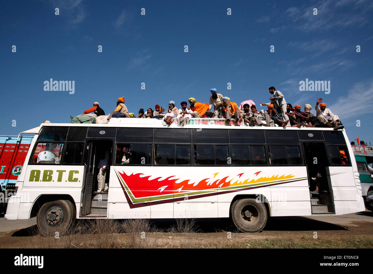 People travelling sitting on top of bus in Punjab ; India Stock Photo