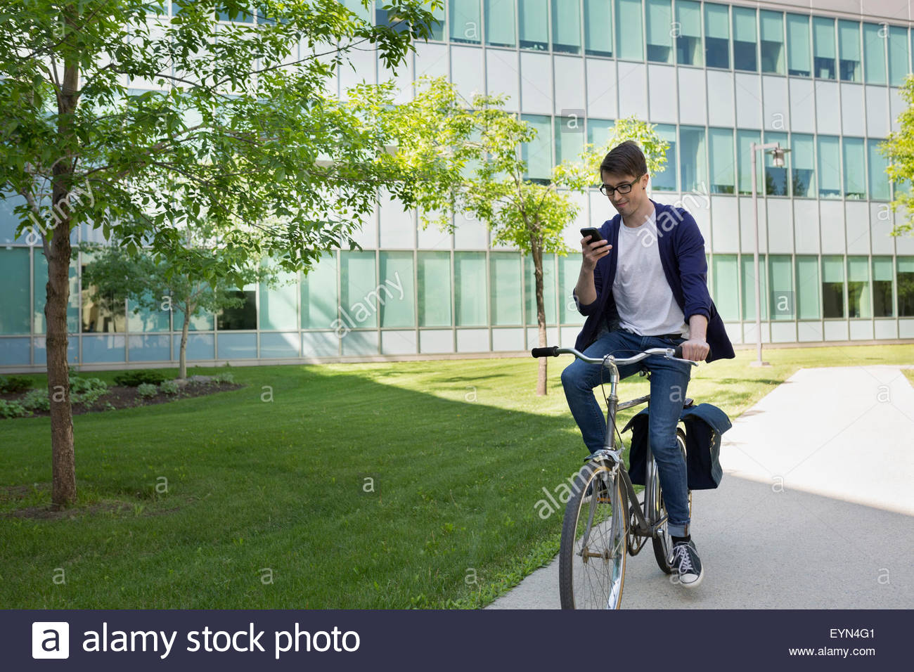 College student riding bike on campus and texting Stock Photo, Royalty