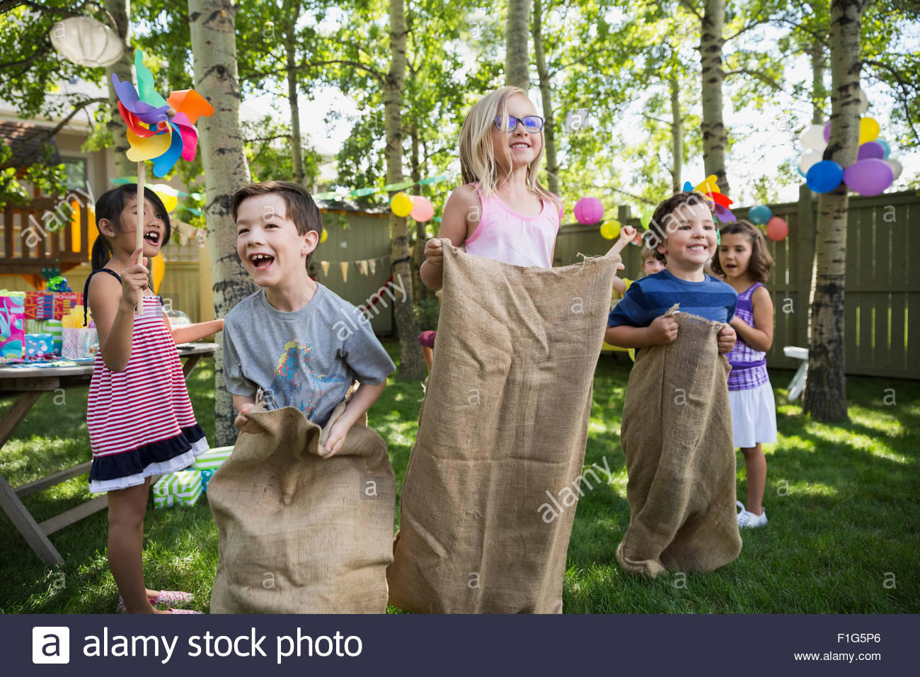 Kids Enjoying Sack Race At Backyard Birthday Party Stock Photo