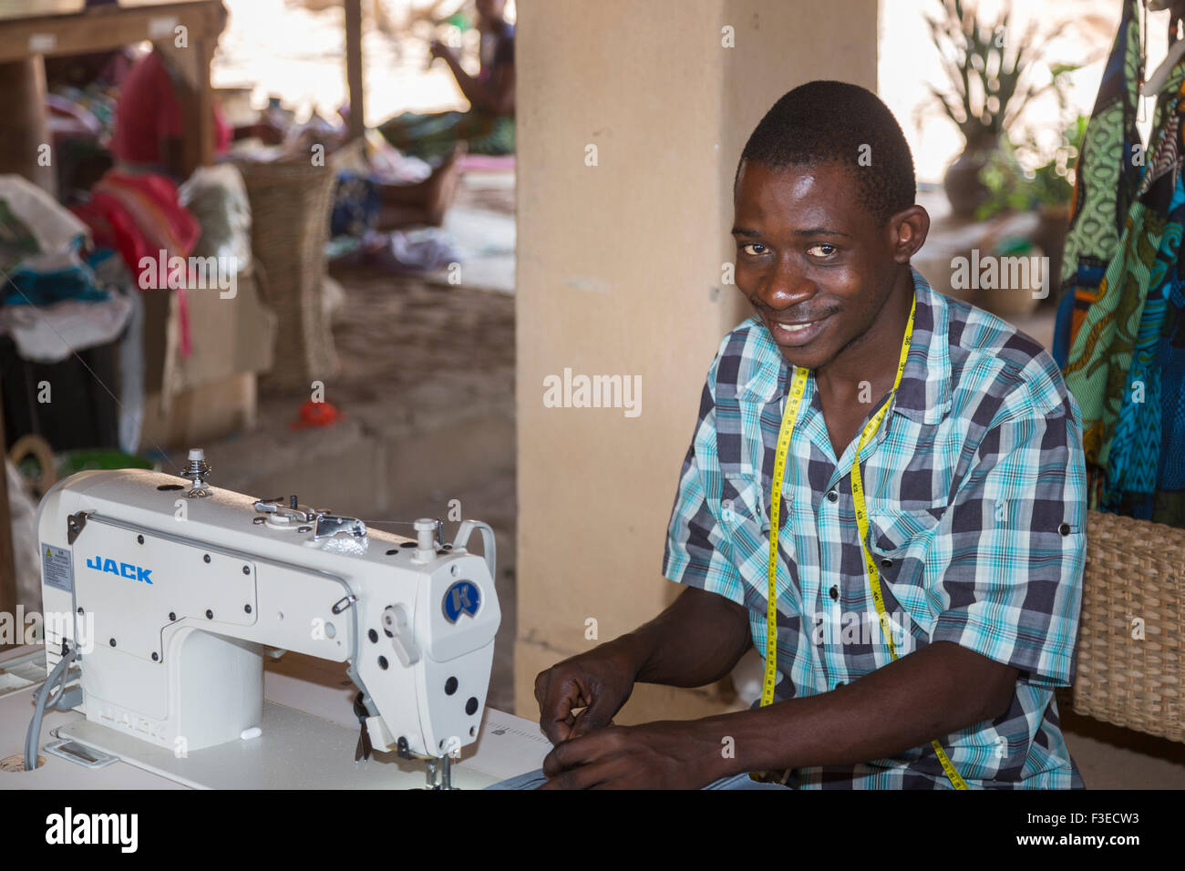 Smiling local African man sewing with a sewing machine at Katundu Stock