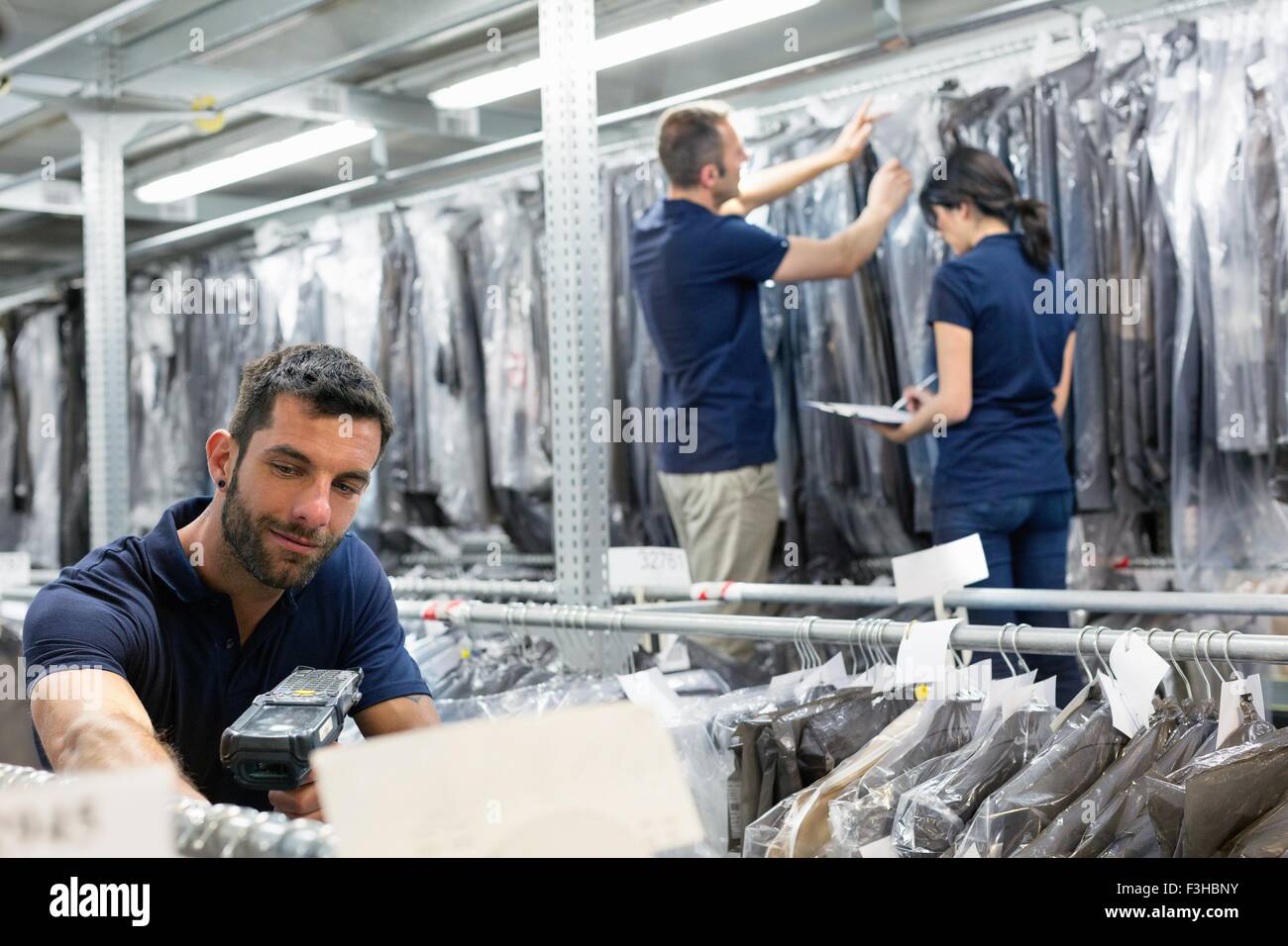Three warehouse workers preparing garments in distribution warehouse Stock Photo, Royalty Free