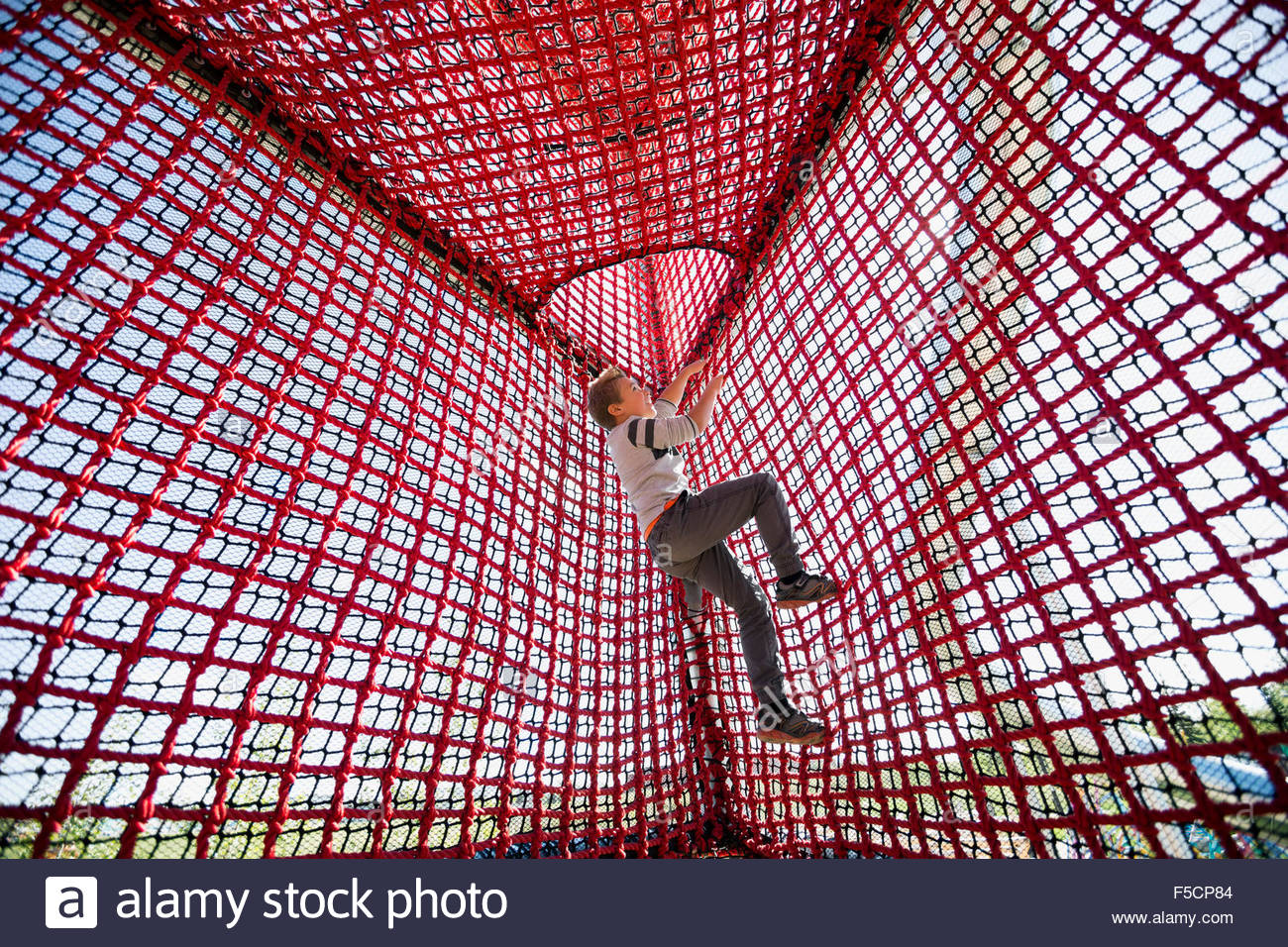 Boy climbing rope net at sunny playground Stock Photo, Royalty Free