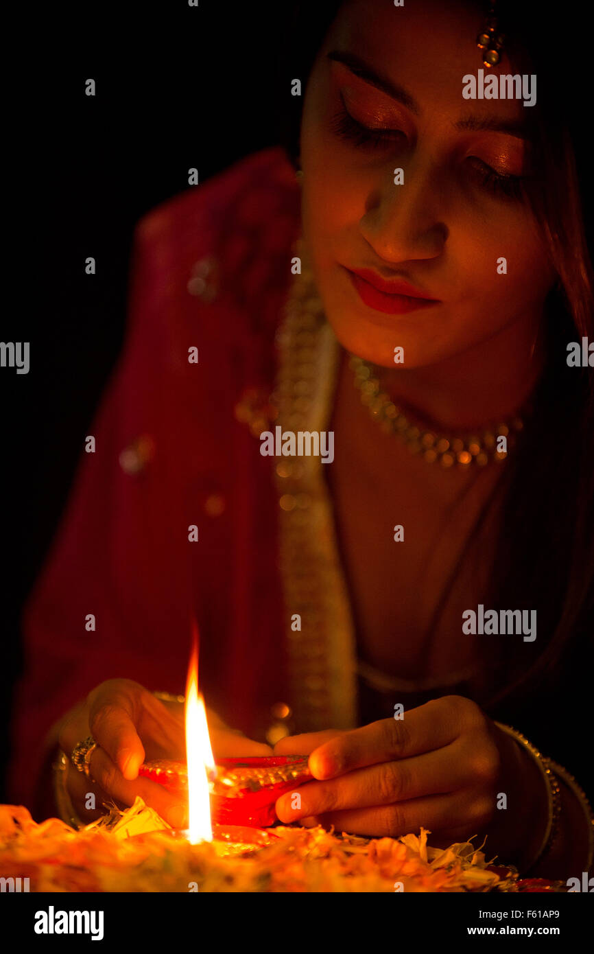 Traditional Indian woman lighting Diya during Diwali Festival in