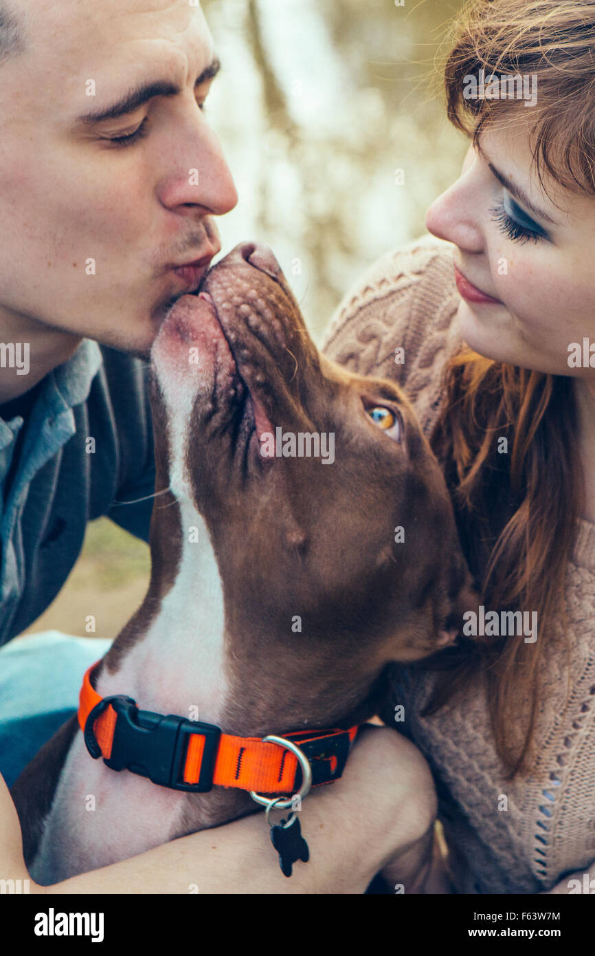 Couple in love with dog nature dog licking man outdoor lake park Stock Photo - couple-in-love-with-dog-nature-dog-licking-man-outdoor-lake-park-F63W7M