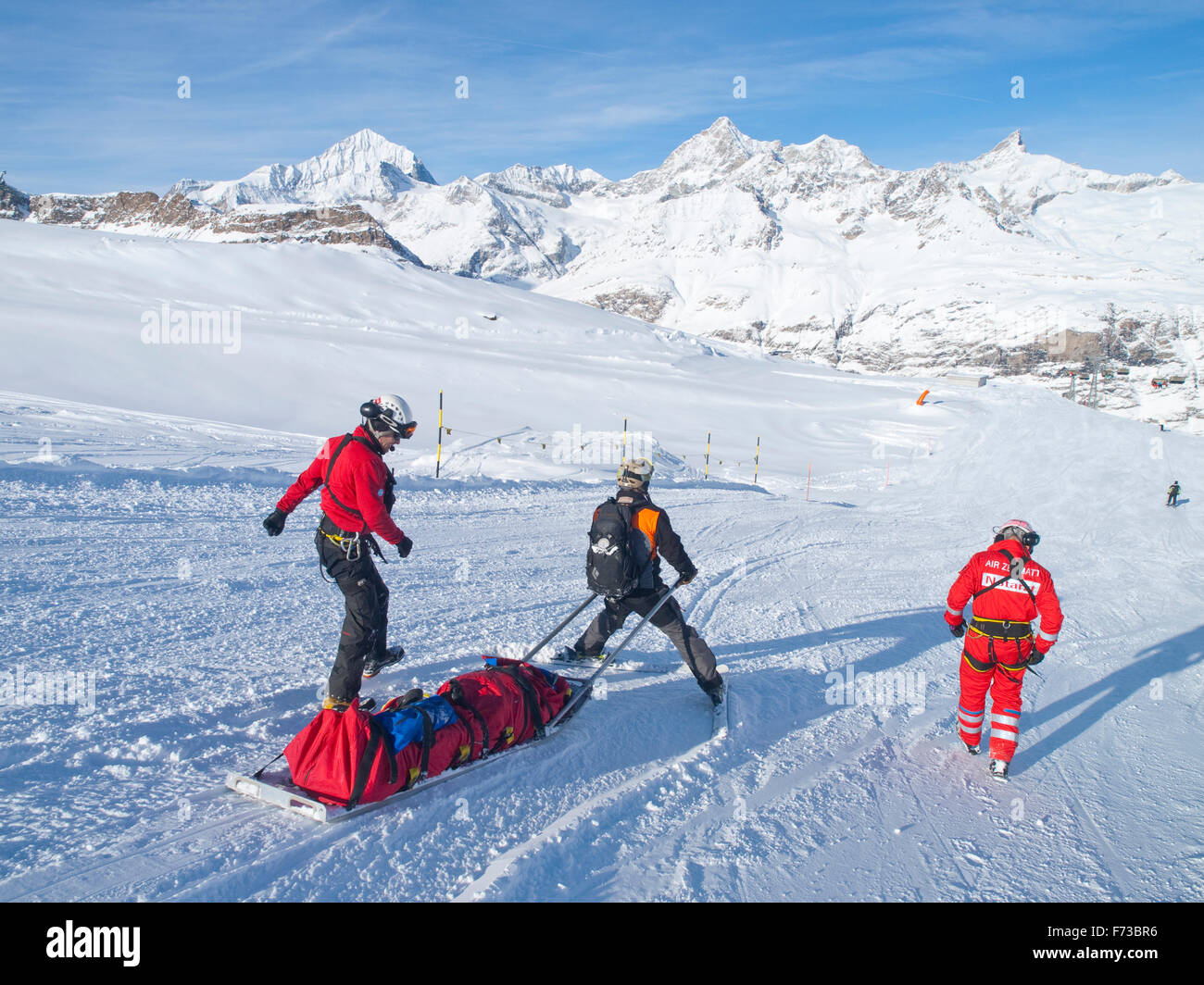 A rescue team is transporting a wounded skier on a rescue sled down