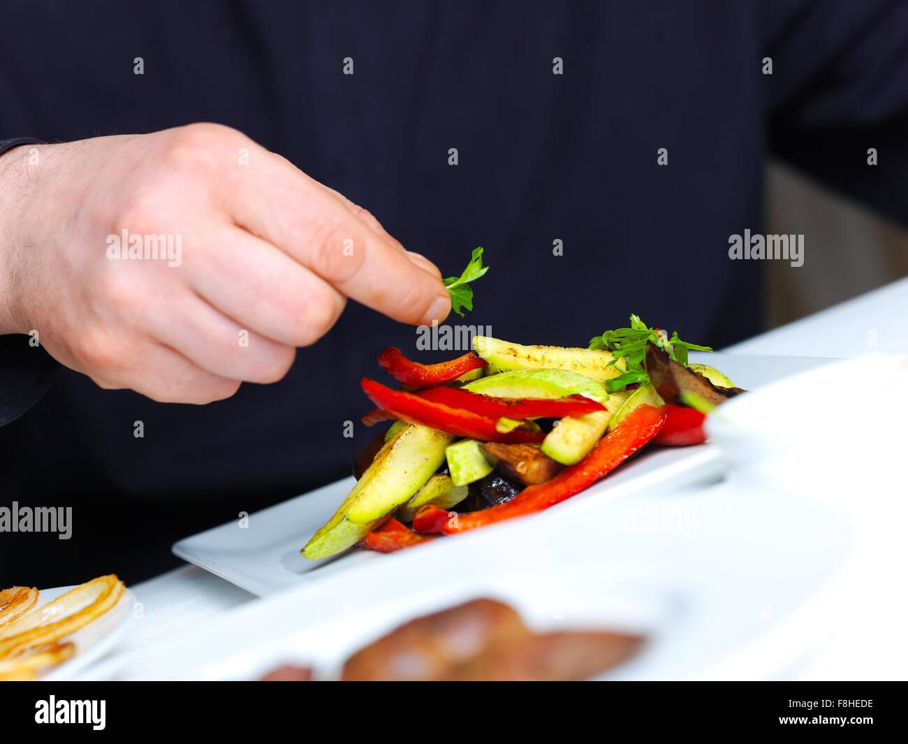 handsome chef dressed in black uniform decorating tasty food in handsome chef dressed in black uniform decorating tasty food in