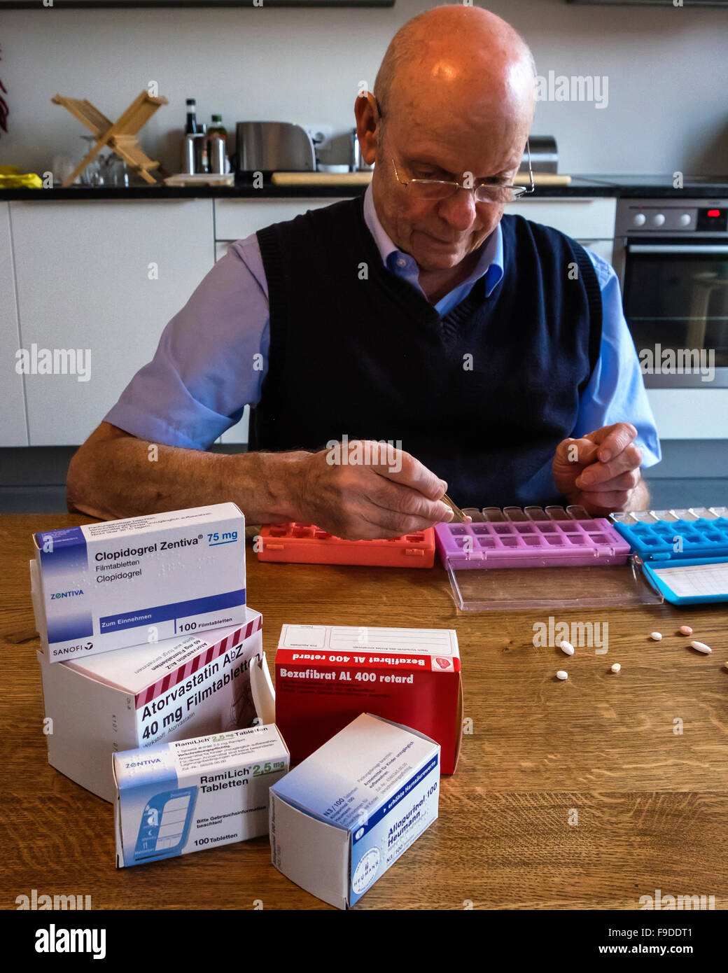 Senior elderly man sorting prescription medicine into pill boxes Stock