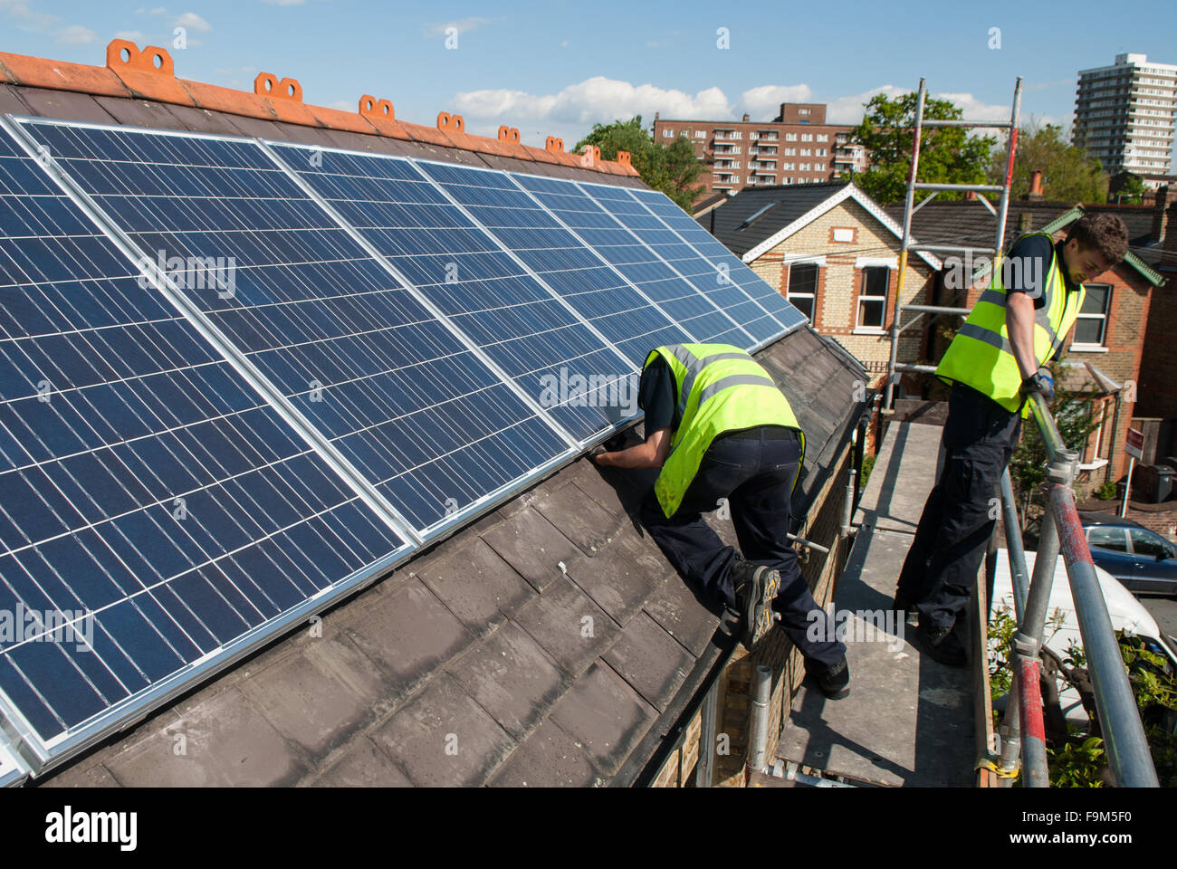 Workers install photovoltaic solar panels on the slate roof of a Stock