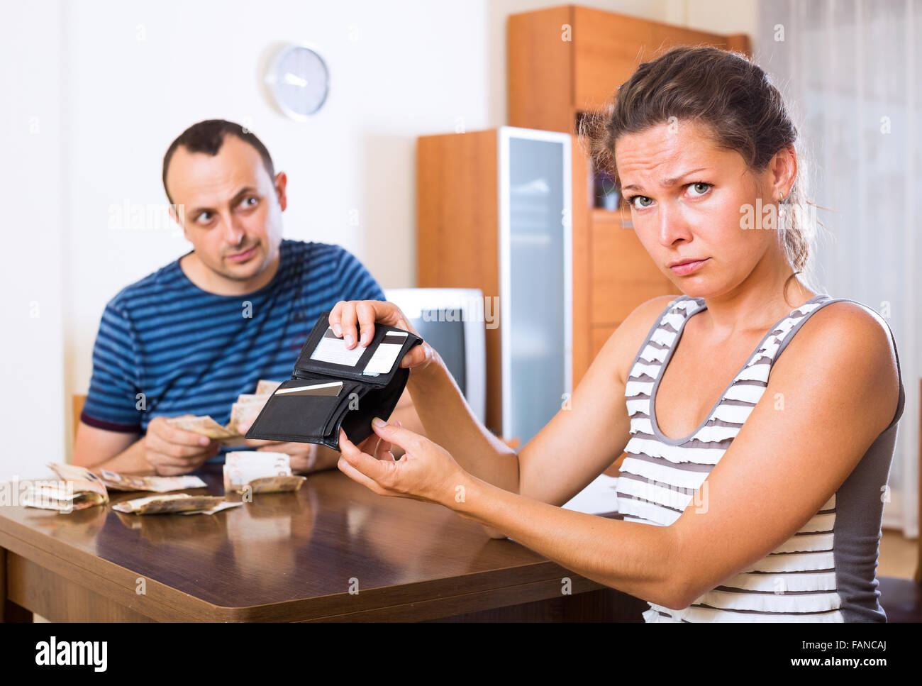 Sad young woman and her husband counting money for paying debt image