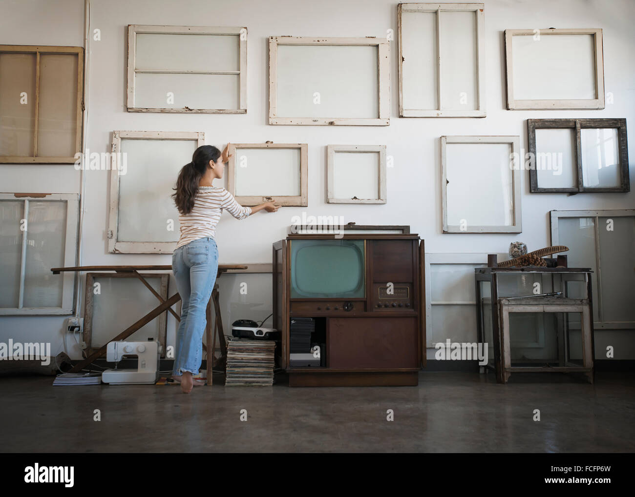 Loft decor. a woman hanging picture frames, blank canvases on a ...