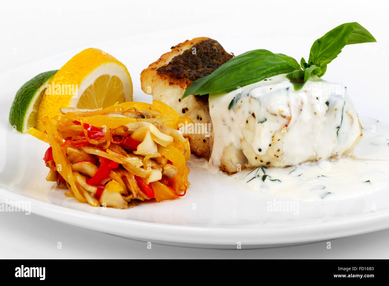 Grilled fish with sauce, vegetable salad and lemon Stock Photo, Royalty