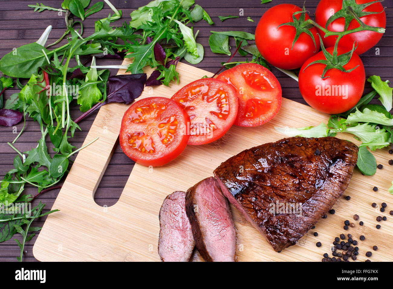 close-up of medium rare roast beef with fresh herbs and vegetables