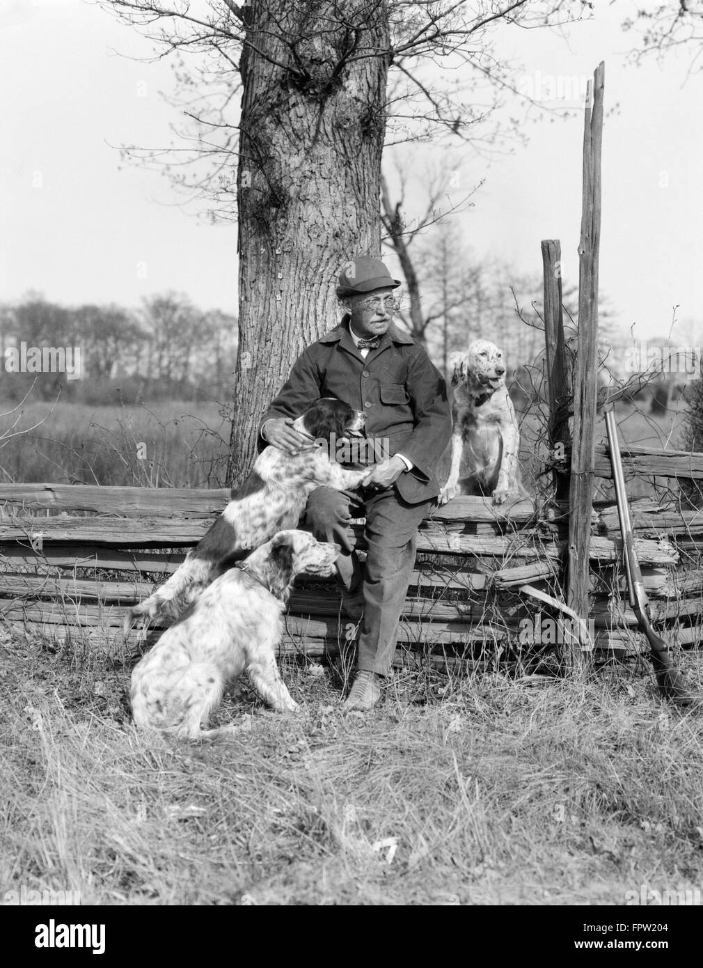 1920s 1930s SENIOR MAN HUNTING CLOTHES SITTING SPIT RAIL FENCE WITH Stock Photo, Royalty Free