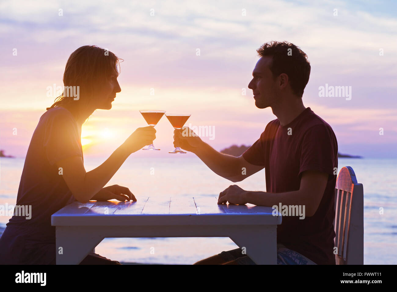 couple in restaurant, drinking cocktails on the beach at sunset Stock
