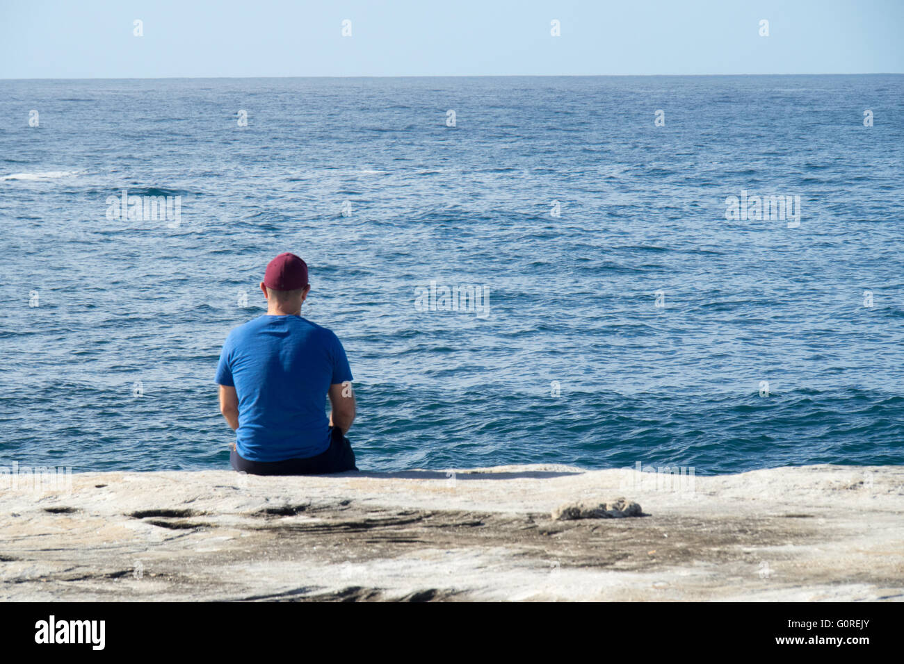 A Man Sitting At The Cliffs Edge Looking Out To Sea A Man Sitting At The Cliffs Edge Looking Out To Sea