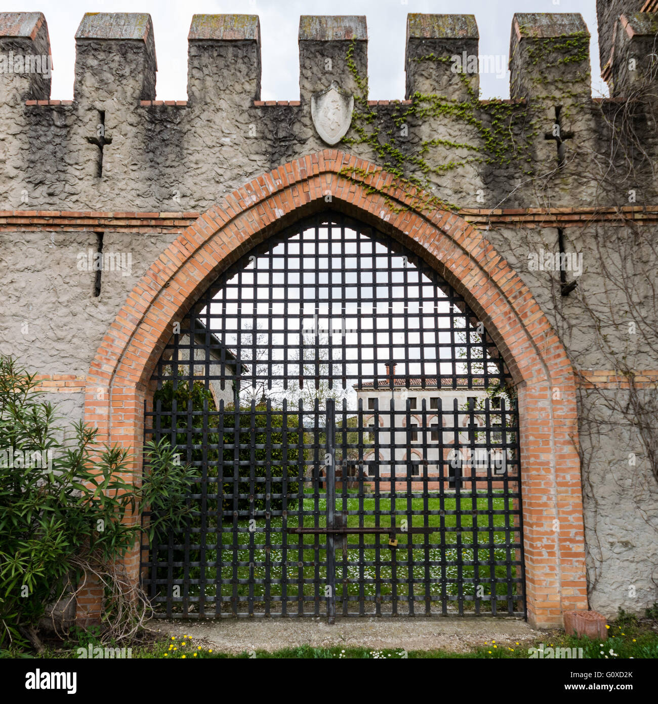arched entrance of a medieval castle closed by an iron grille gate