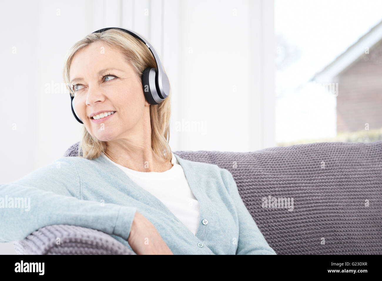 Mature Woman Listening To Music On Wireless Headphones Stock Photo Alamy