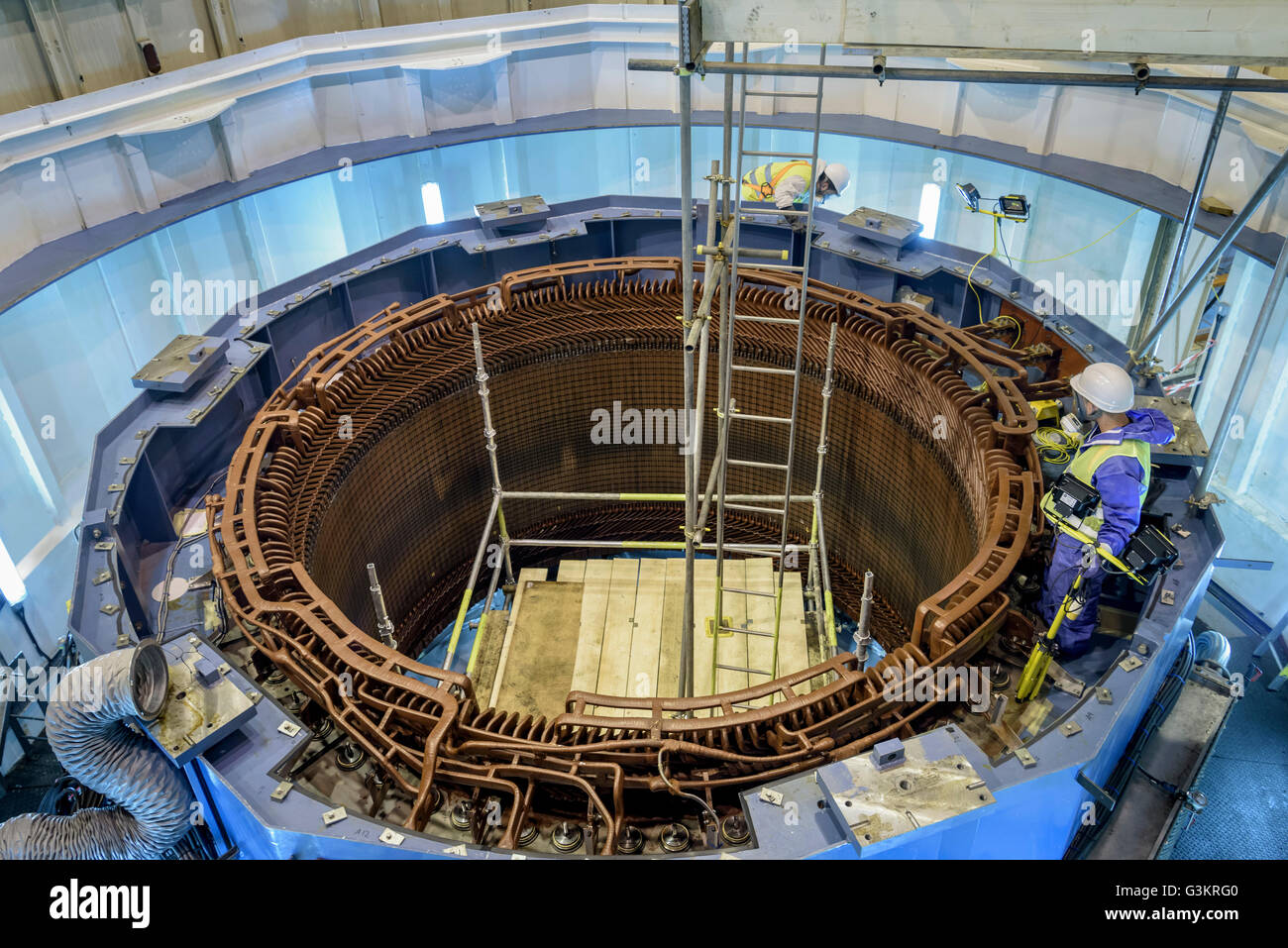 Workers maintaining generator in hydroelectric power station Stock