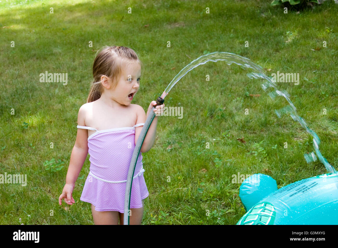 4year old girl filling an inflatable pool with water Stock Photo