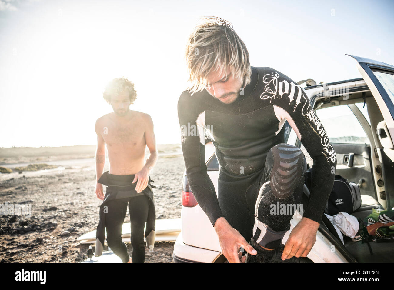 Two men in wetsuits preparing to go surfing at Corralejo in Stock Photo