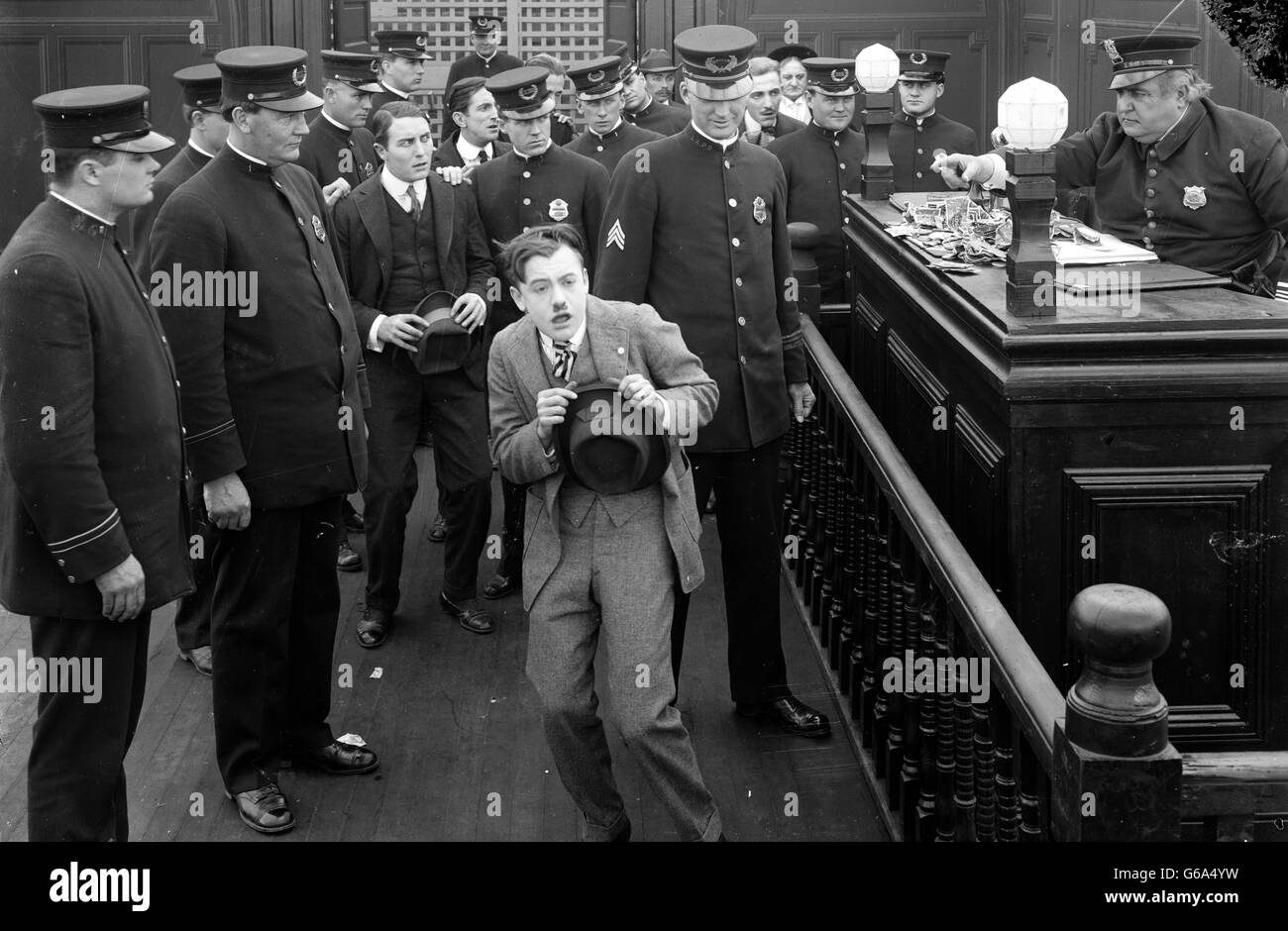 1910s 1920s MAN CRINGING BEFORE POLICE DESK SERGEANT POINTING FINGER