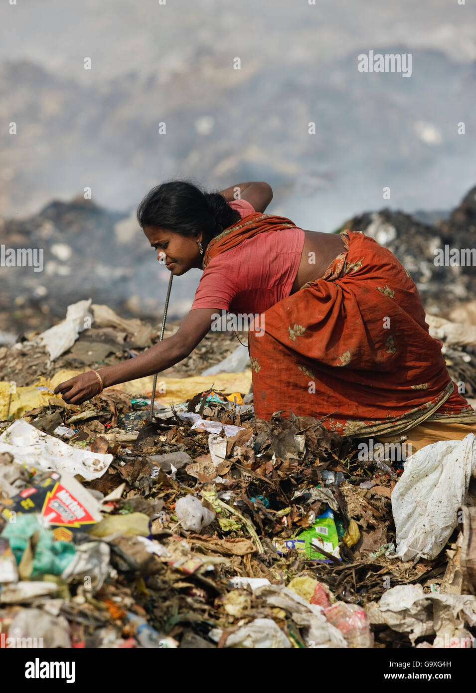 Indian woman in sari picking through rubbish a t a landfill site Stock