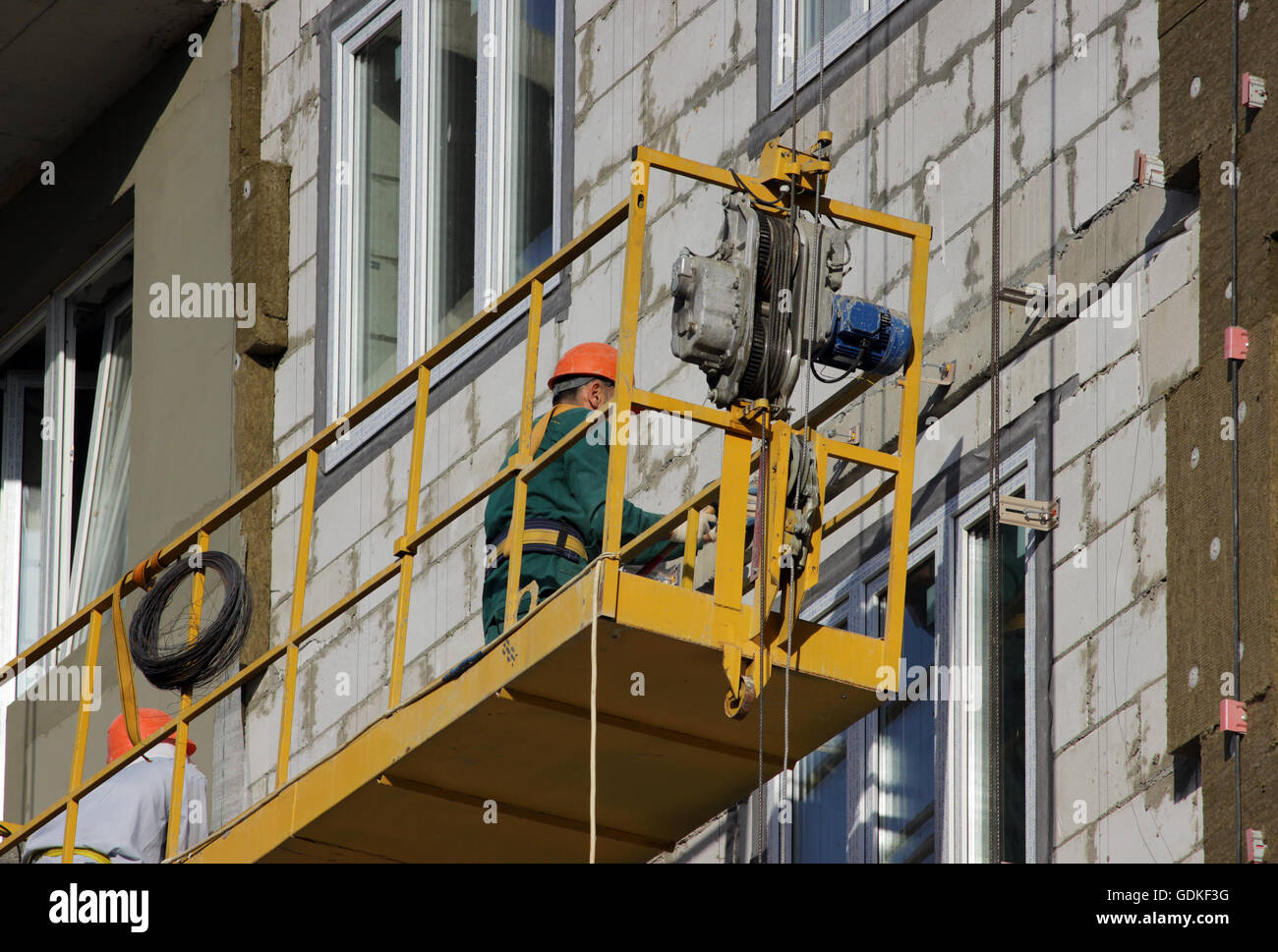 construction suspended yellow cradle with workers on a newly built