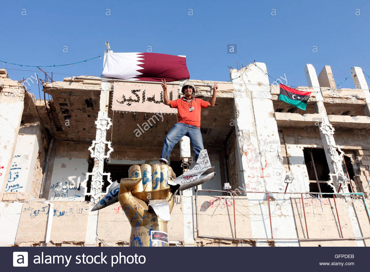 a-rebel-makes-victory-signs-as-he-stands-between-the-qatar-flag-top-GFPDEB.jpg