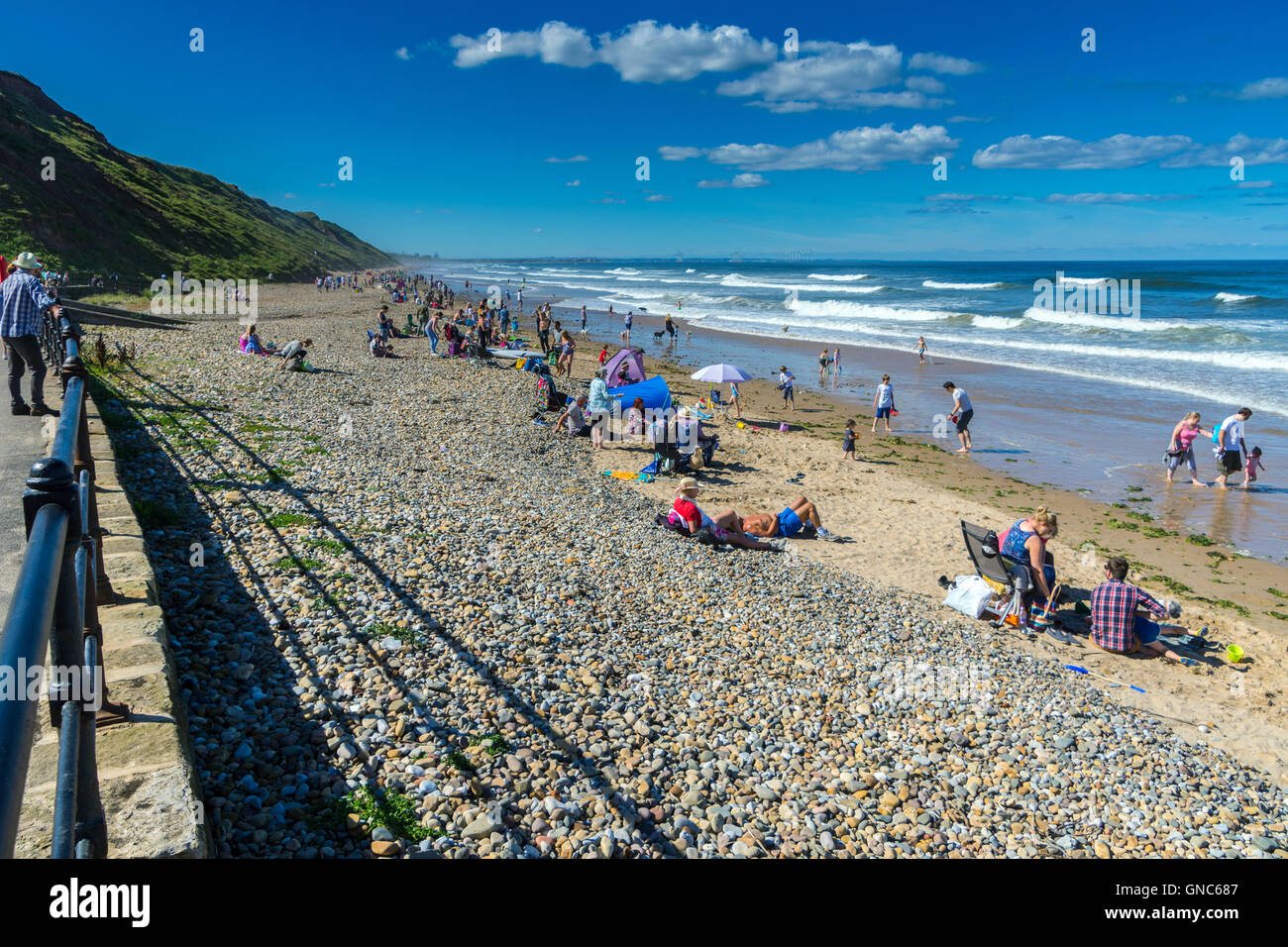 Bank Holiday crowds on sunny pebble beach, Saltburn by the Sea Stock