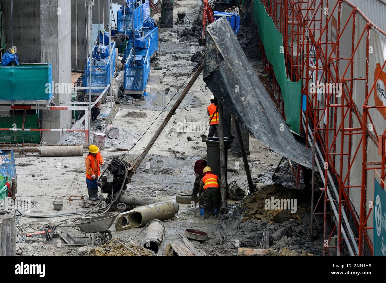 Construction workers at wet building site with scaffolding and tools Stock Photo, Royalty Free