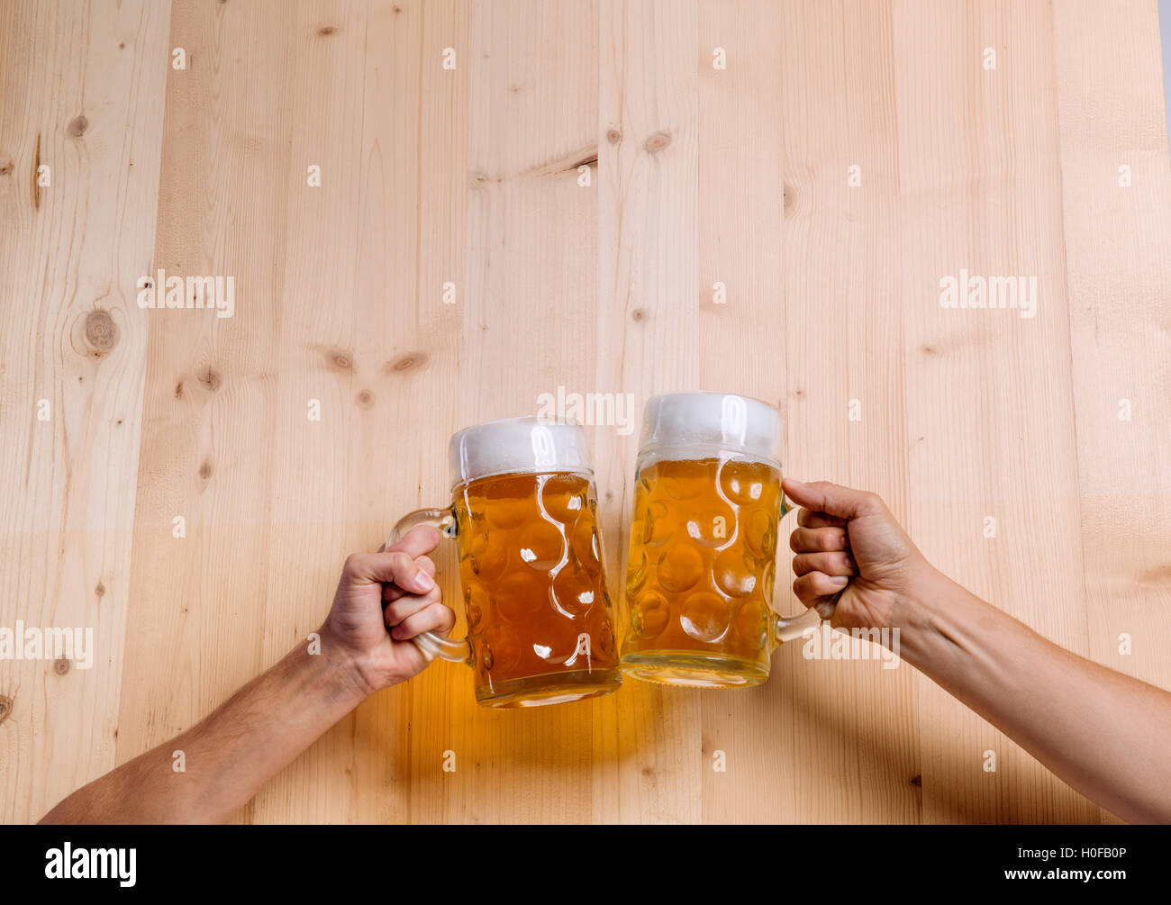 Two unrecognizable men clinking with beer mugs, studio shot Stock Photo
