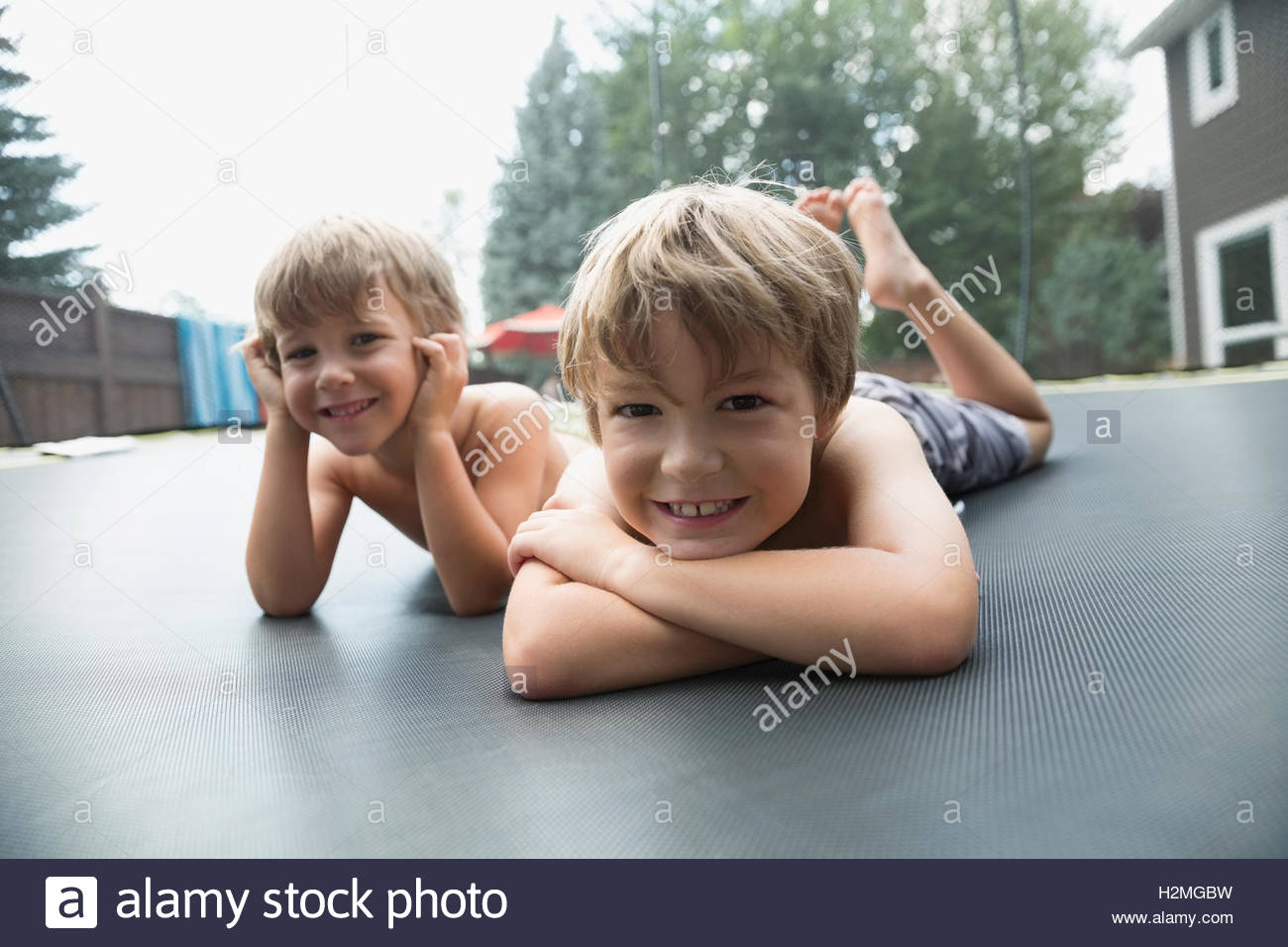 Portrait Smiling Boys Laying On Trampoline In Backyard Stock Photo