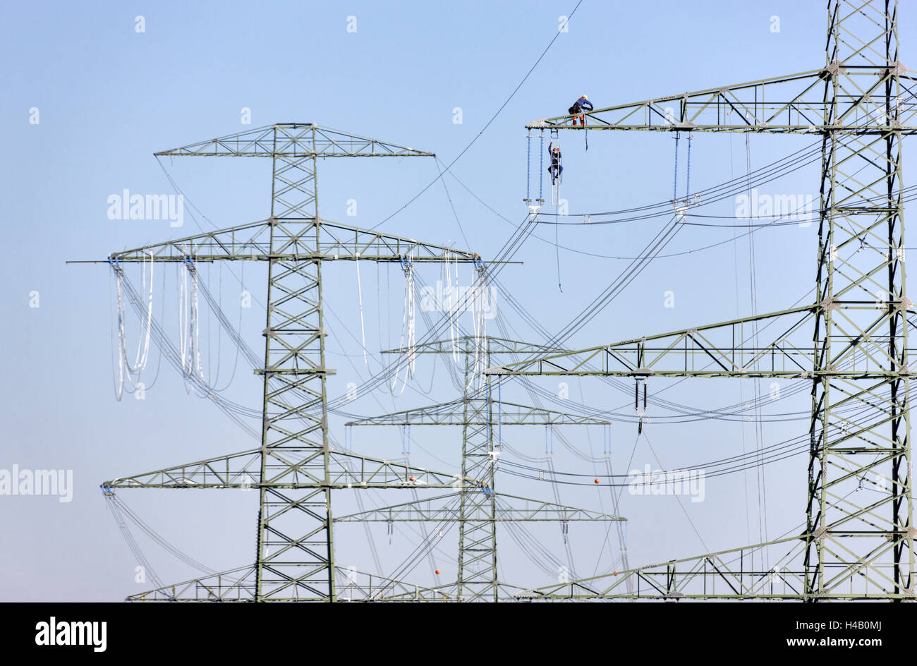 Highvoltage poles, wires, power line installation, man climbing to