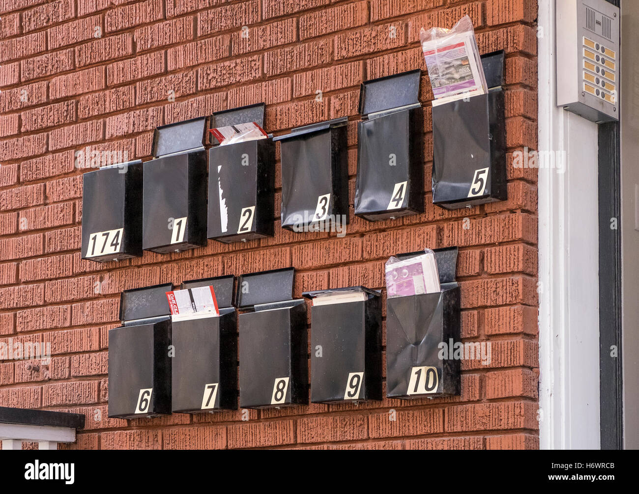 Apartment Building Mailboxes black metal mailboxes hang on a red brick wall outside an Apartment Building Mailboxes black metal mailboxes hang on a red brick wall outside an