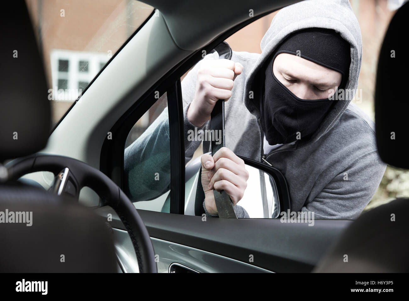 Masked Man Breaking Into Car With Crowbar Stock Photo