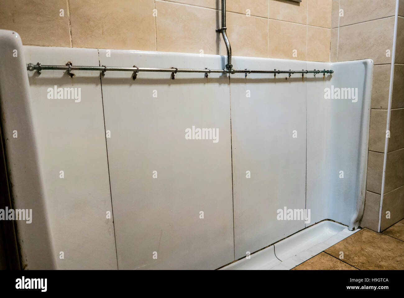 An old fashioned ceramic trough urinal in a British pub Stock Photo