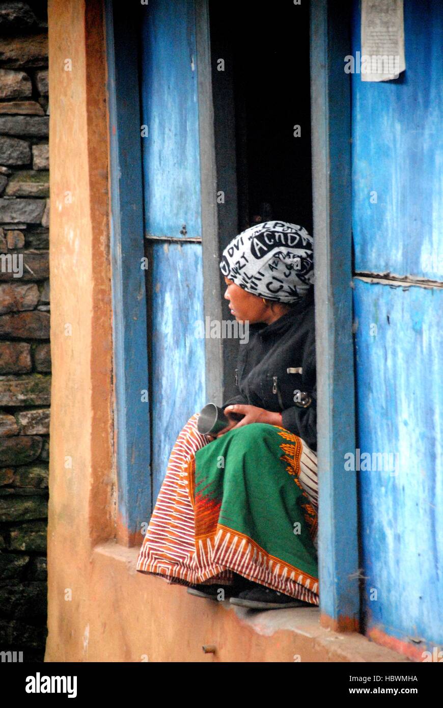 Nepalese woman sitting in the front door l looking at the street ... Nepalese woman sitting in the front door l looking at the street ...