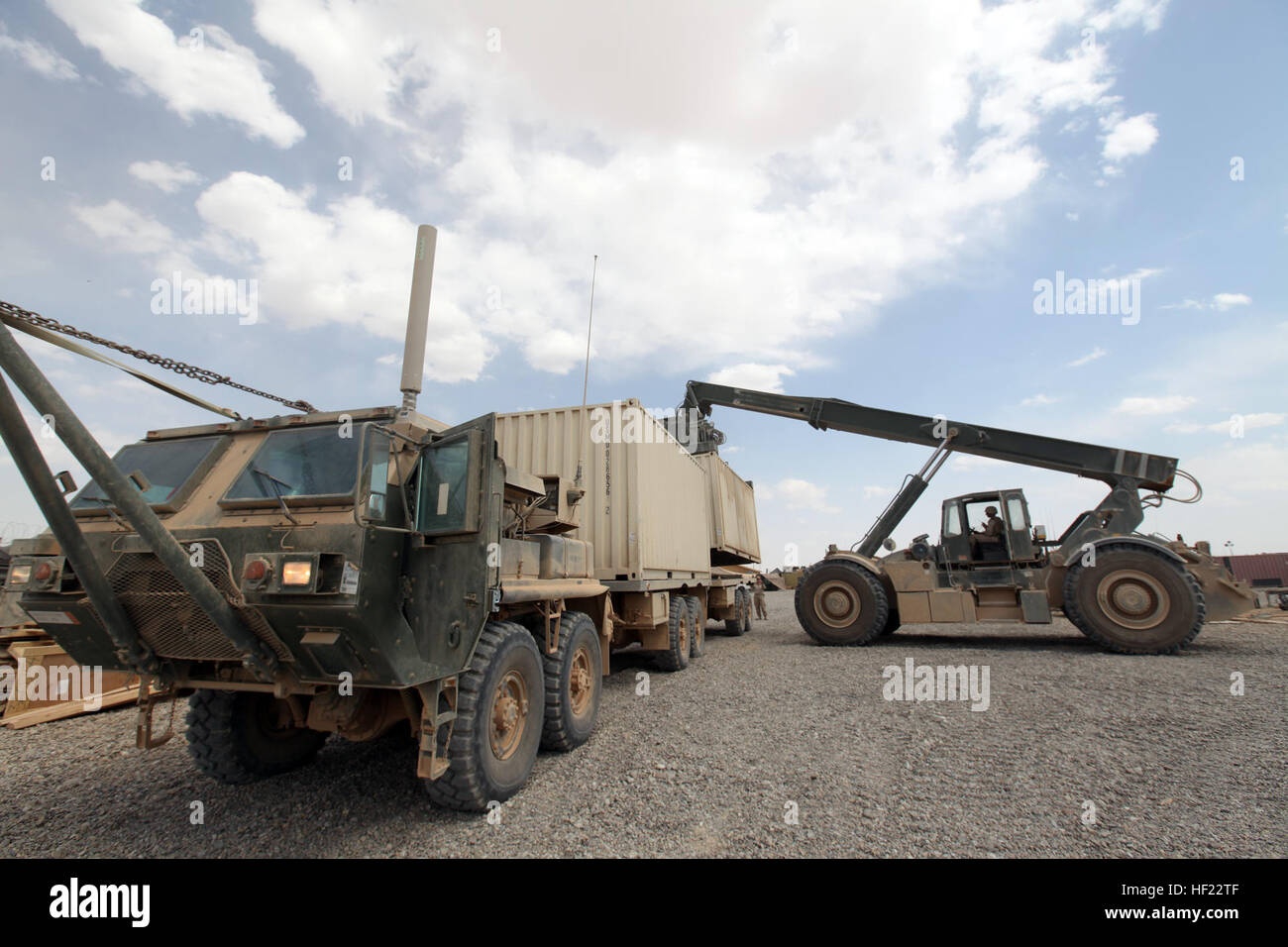 A Rough Terrain Container Handler loads a supply container onto a Stock