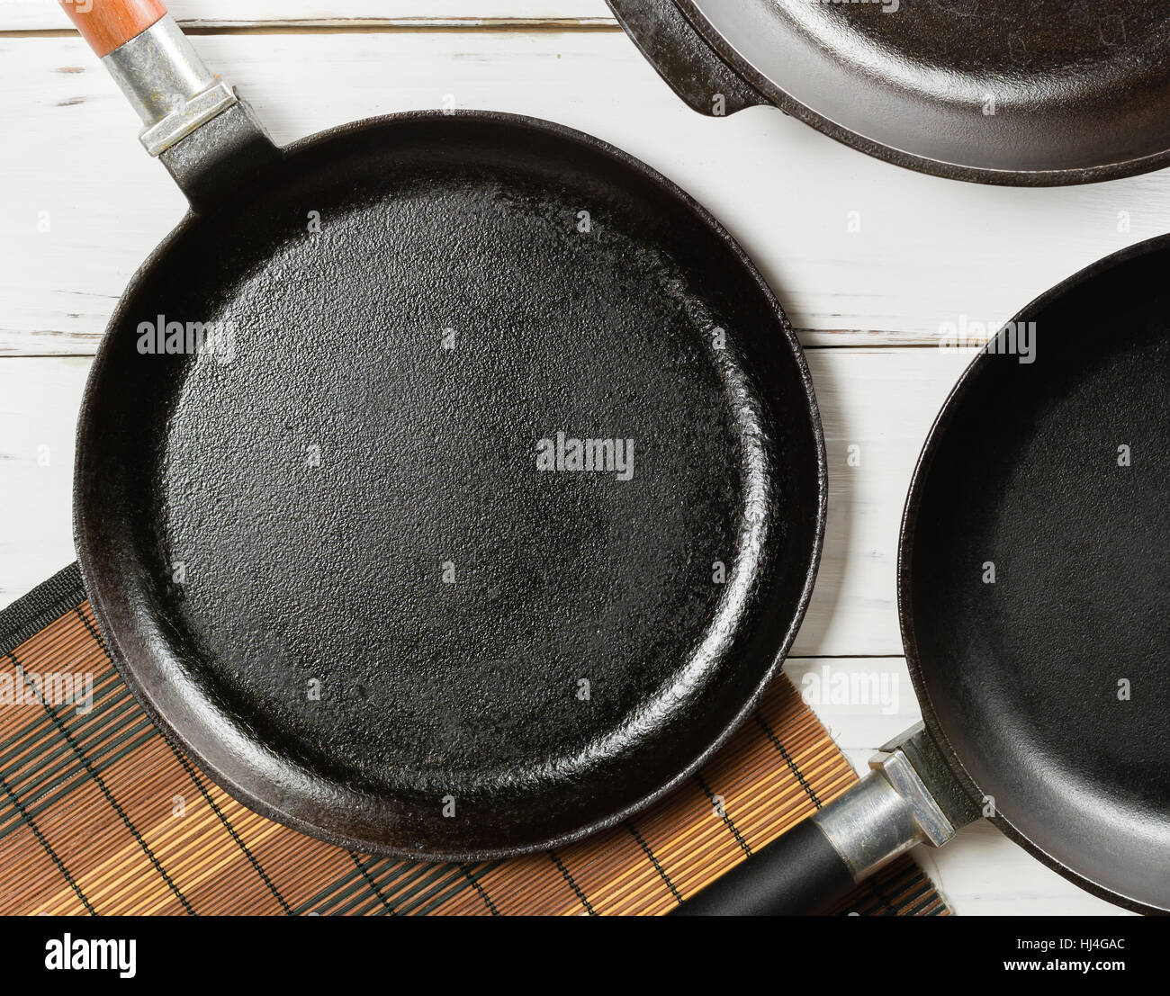 Several Empty Cast Iron Frying Pans On A White Wooden Background View