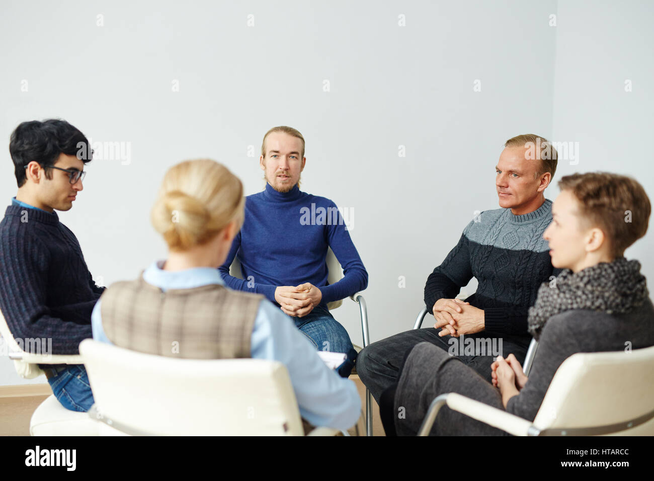 Group of people sitting in circle on chairs in psychological support