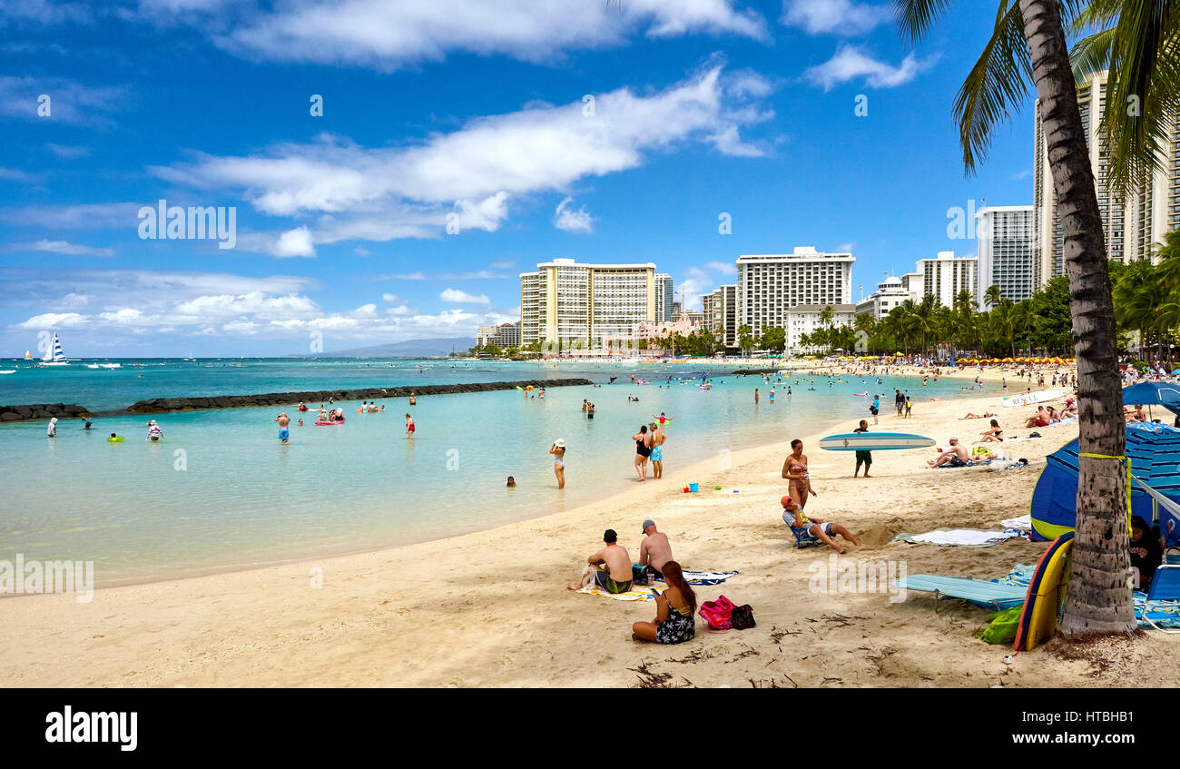 tourists and locals enjoy the white sand beaches of Waikiki in Hawaii