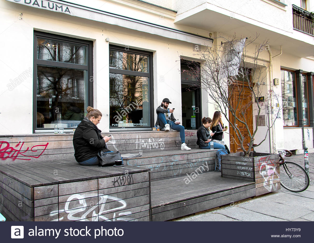 Hipster berlin coffee shop trendy young people coffeehouse texting smartphone looking at cell phone using iphone user