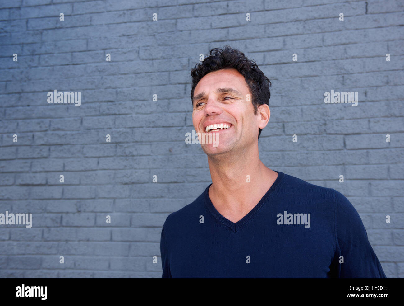 Close Up Portrait Of A Handsome Mature Man Smiling Against Gray Wall