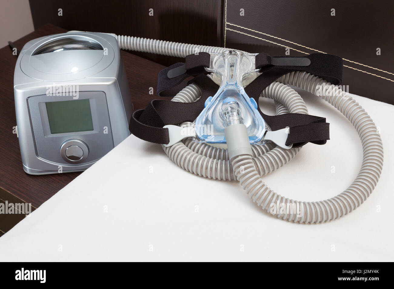 Sleep Apnea CPAP mask, hose, headgear, and machine on bed, selective
