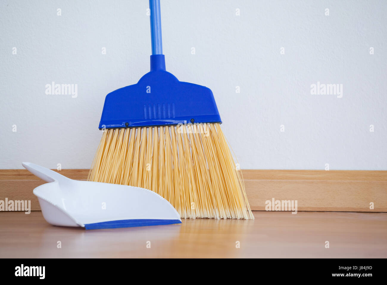 close-up of dustpan and sweeping broom on wooden floor stock photo close-up of dustpan and sweeping broom on wooden floor stock photo