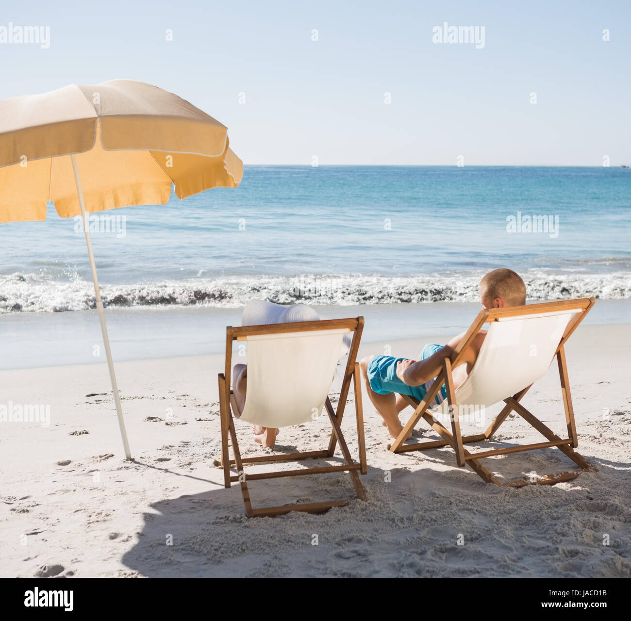 Cute couple on the beach sunbathing on their deck chairs Stock Photo