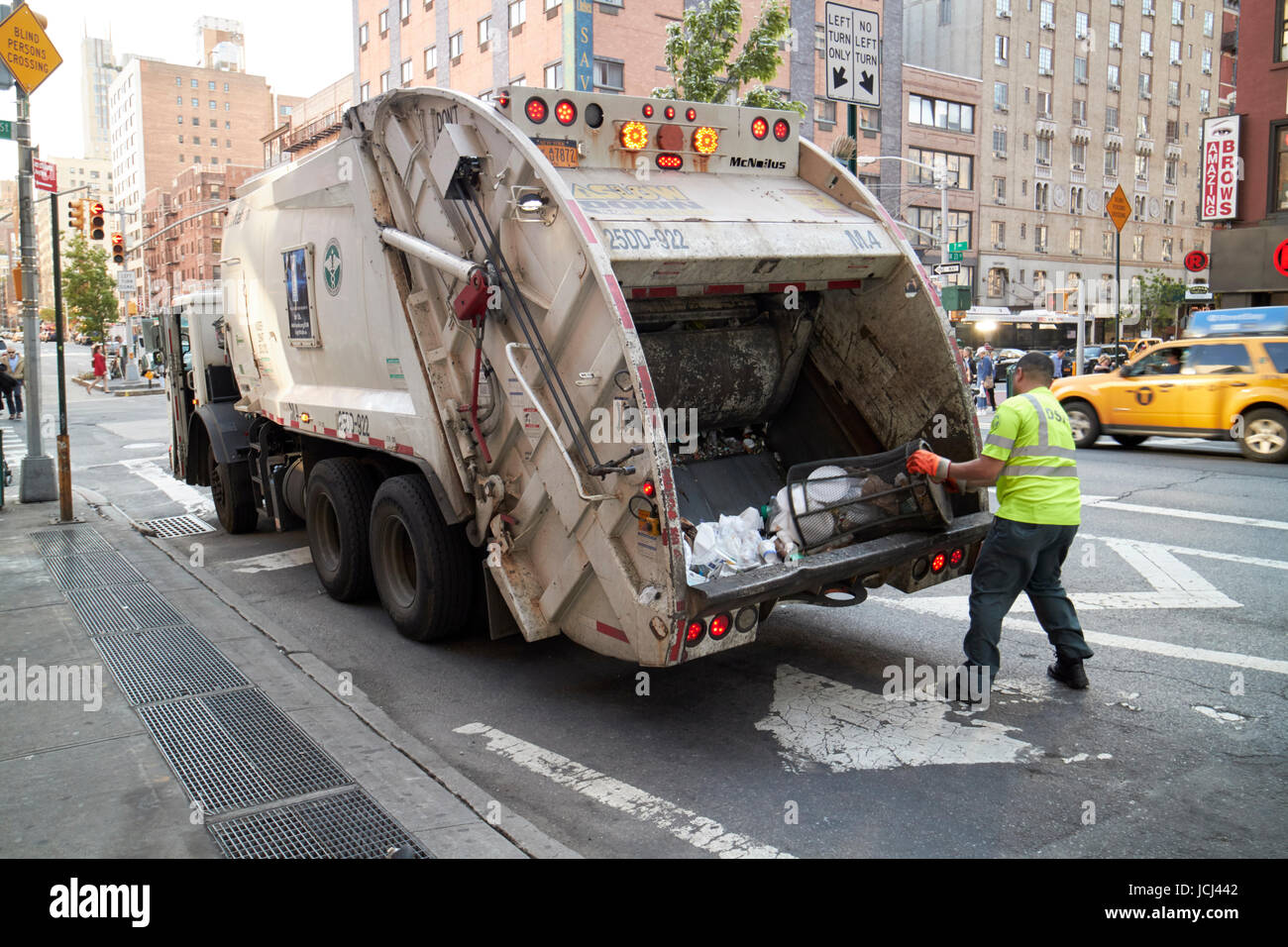 New York City sanitation truck worker emptying street bins new york