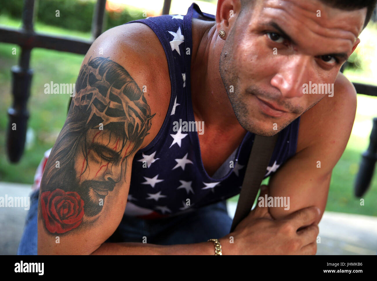 a man with a tattoo of the image of jesus on his arm poses in a man with a tattoo of the image of jesus on his arm poses in