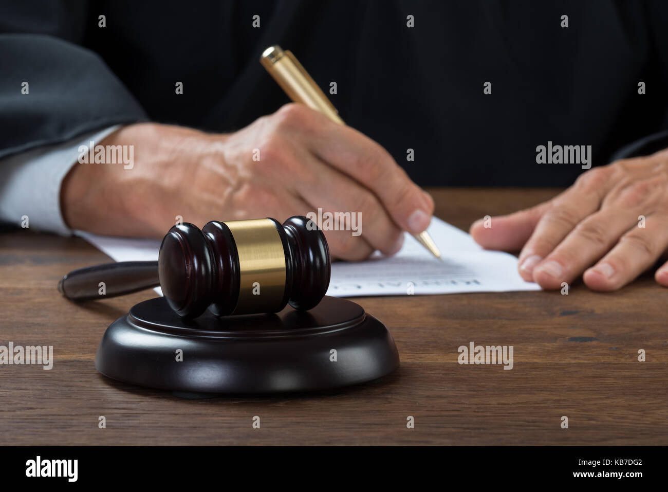 Midsection Of Judge Writing On Paper At Table In Courtroom Stock Photo